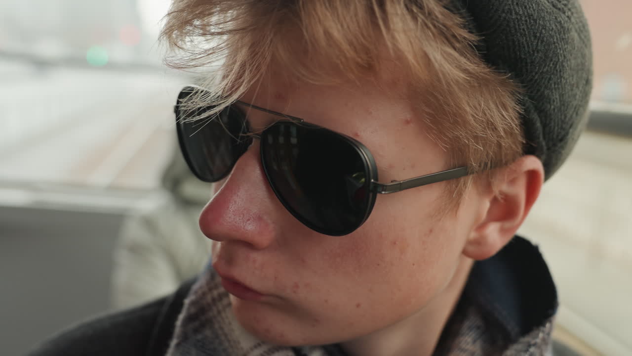 Youthful artist portrait. Closeup of young designer on subway. Focused young creator with reflective window background. Creative young individual captures introspection during city transit ride