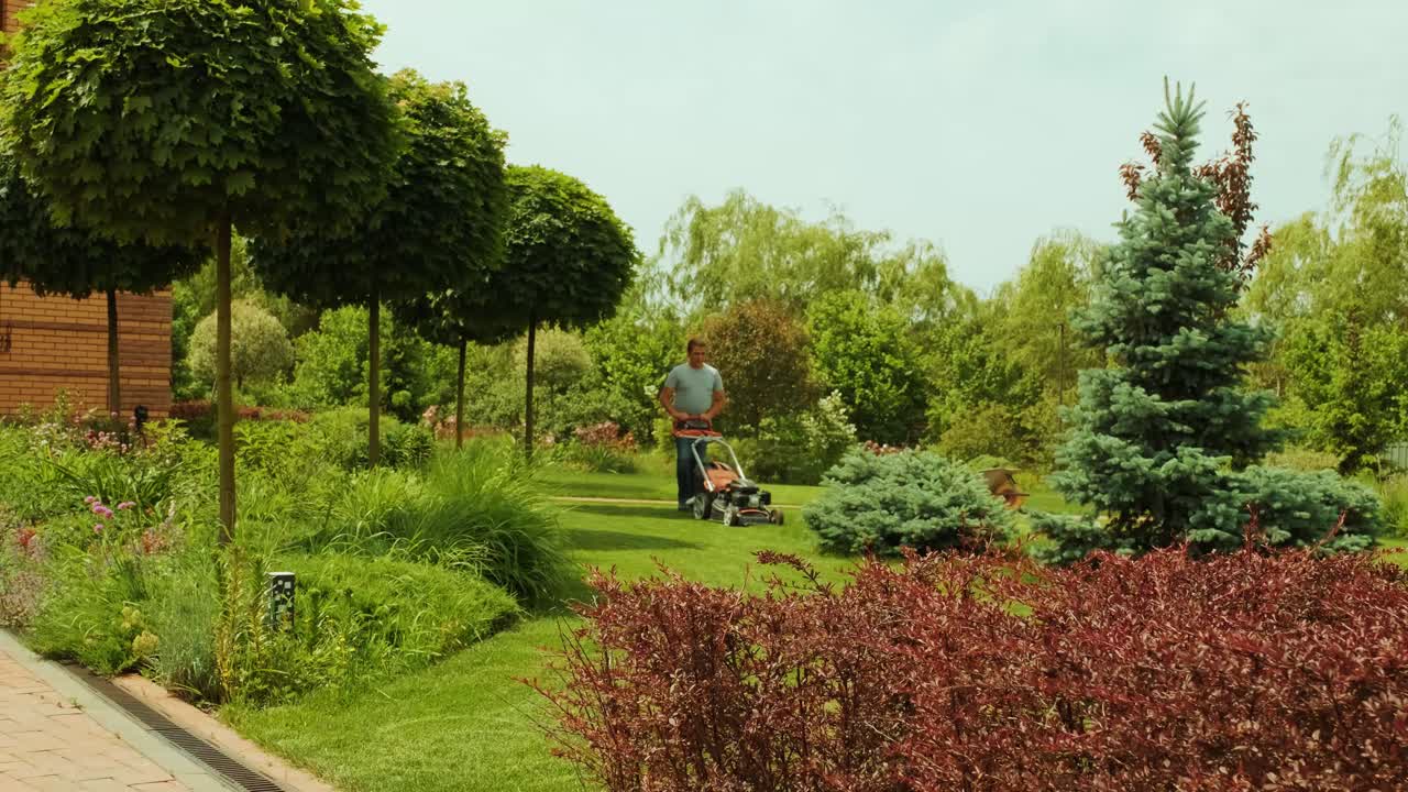 Lawn mower cutting the grass. Gardening activity. Cutting grass with petrol driven lawn mower in sunny garden. Gardener working with  mower machine in the garden. Lawn mower cutting green grass