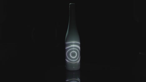 una luz giratoria se proyecta en una botella blanca