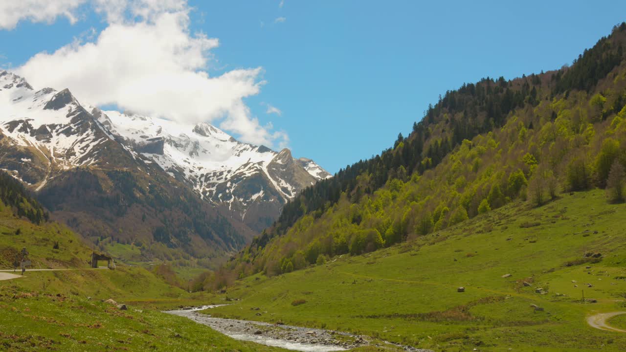 Una valle tra montagne innevate nei Pirenei, attraversata da un piccolo fiume.