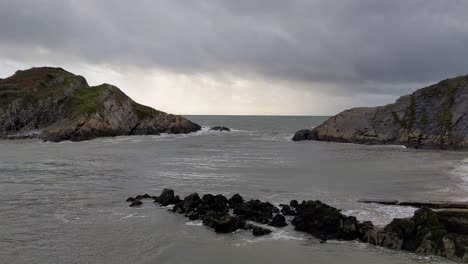 Inselleuchtturmschwenk-An-Erodierten-Felsen-Vorbei-Mit-Dynamischer-Wolkenlandschaft-Und-Rauen-Meereswellen-4k