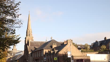 panning shot of church steeple along the river and trees of inverness, scotland in the highlands