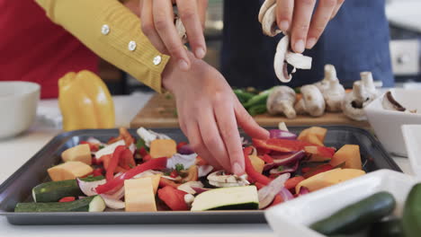 Happy caucasian lesbian couple preparing food and using tablet in sunny kitchen