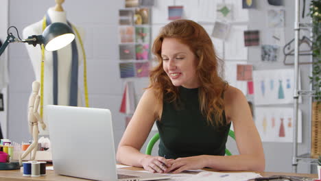 female business owner working in fashion showing designs on video call using laptop