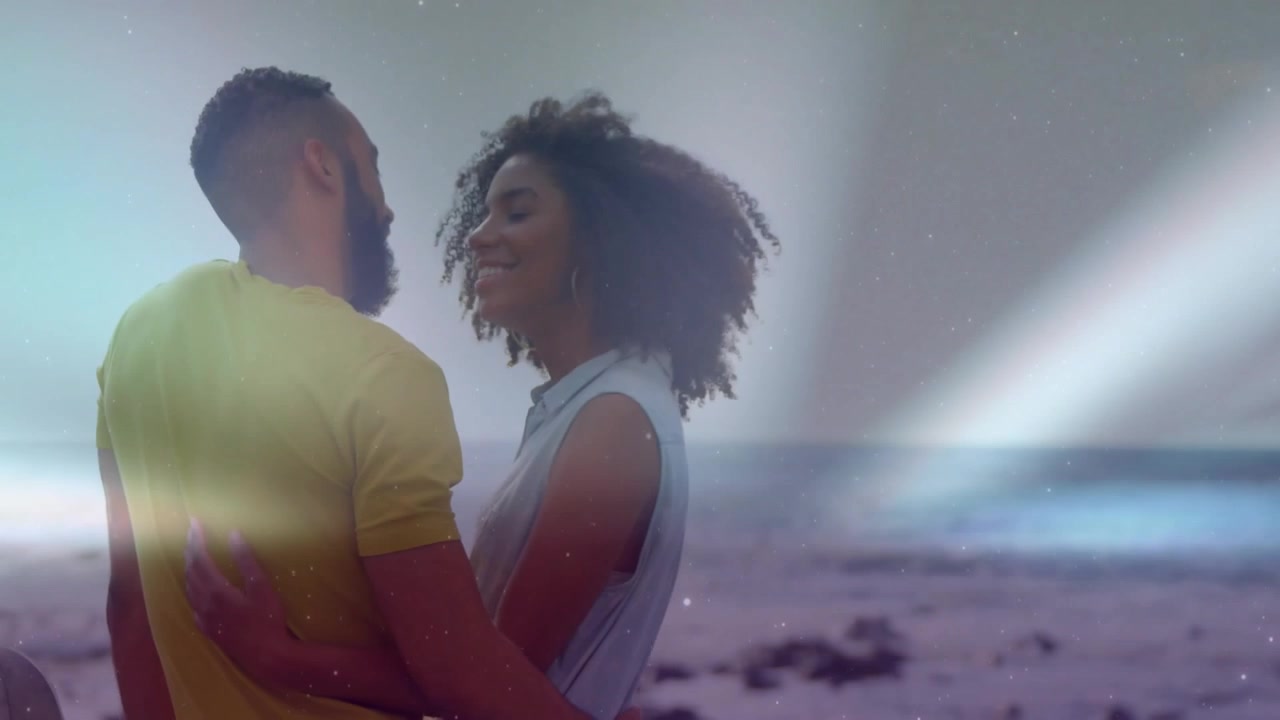 Donna e uomo che si abbracciano in spiaggia, telecamera che si allontana, bagliori che attraversano la coppia, per marketing.