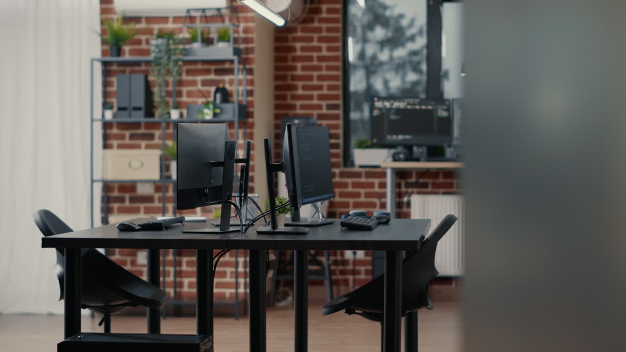 Computer screens on desk in empty data room and computers in background running programming code