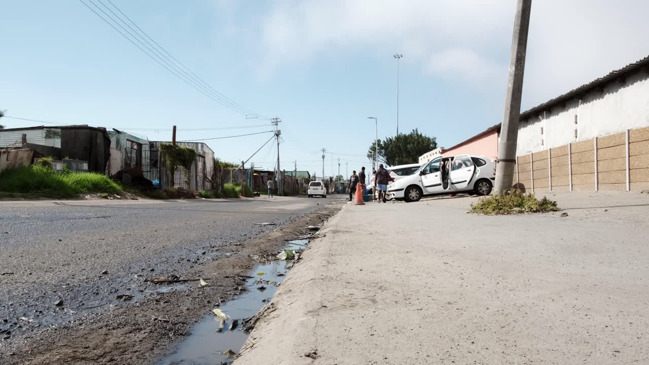 A wide low angle of a car wash operation in the streets of Gugulethu, Cape Town