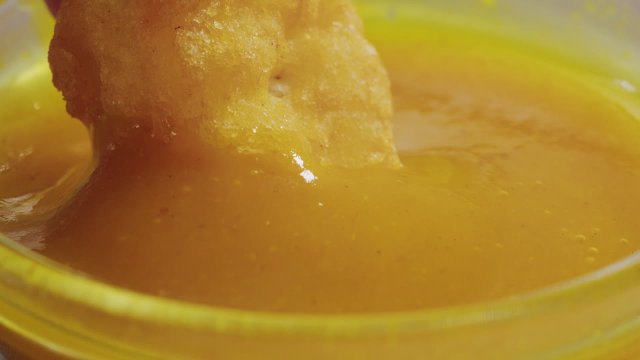 Curry cheese lemon sauce close up, fast food cafe Pouring fries potato and fry chicken in mayo yellow creamy cheese sauce close-up. Eat chicken nuggets with Peruvian sauce. Fast and junk food concept.