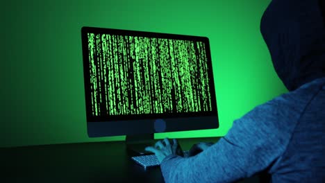 un hombre irreconocible hackeando en una habitación oscura.