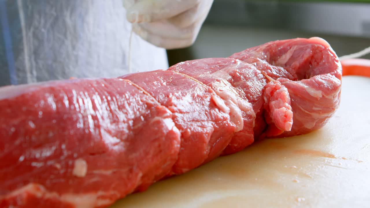 Butcher tying meat with thread in butcher shop 4k