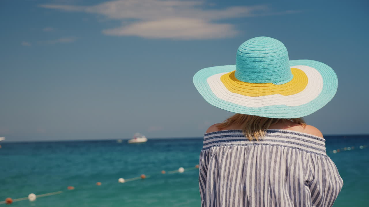 모자를 쓴 여자는 바다를 존경합니다 휴가 개념 4k 비디오 백 뷰에 후면보기 여자