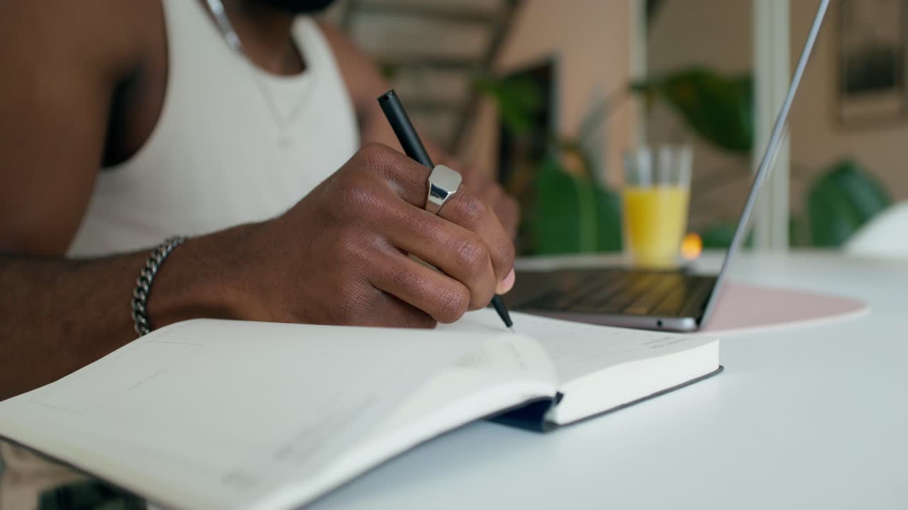 Man working at home with a notebook, laptop, and pen