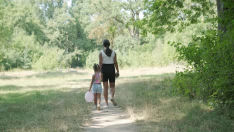 pregnant mother and daughter walking on nature trail