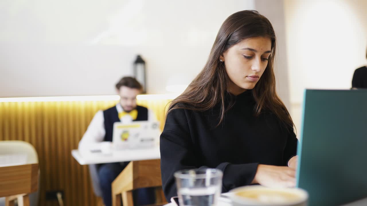 mujer joven trabajando en una computadora portátil en una cafetería