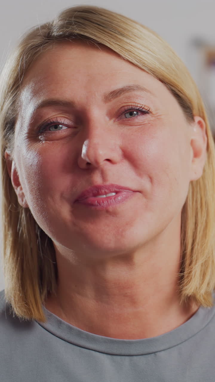 Joyful fashion designer laughing warmly with eyes closed while holding sewing scissors, standing in creative workspace filled with colorful inspiration boards and materials, exuding happiness