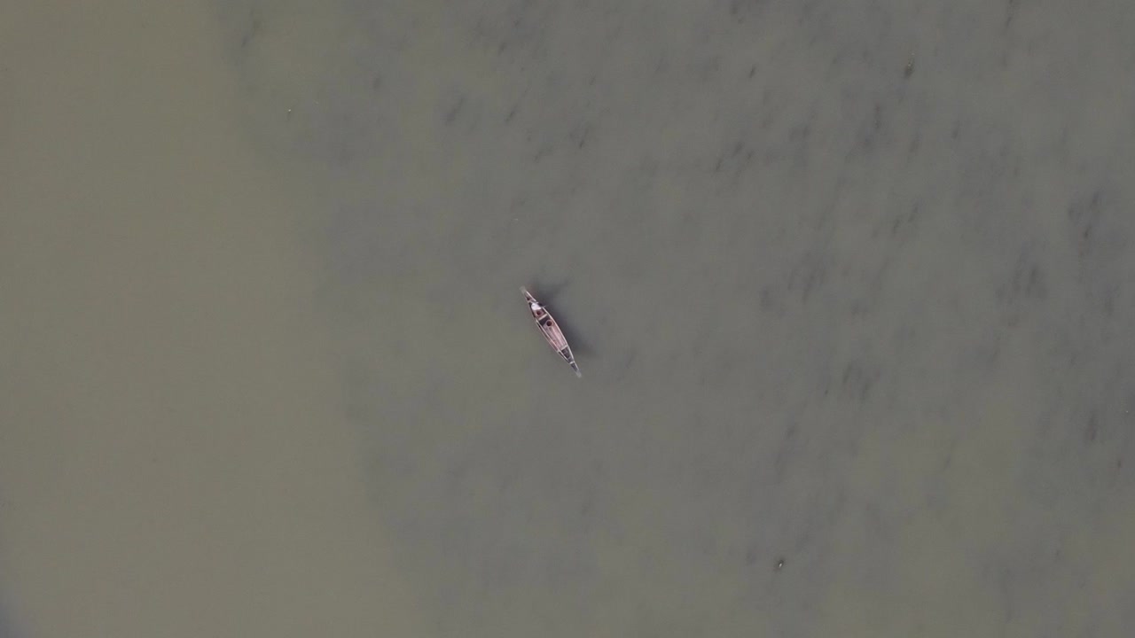 강 위의 전통적인 목조 보트에 외로운 어부의 공중 하향식 전망