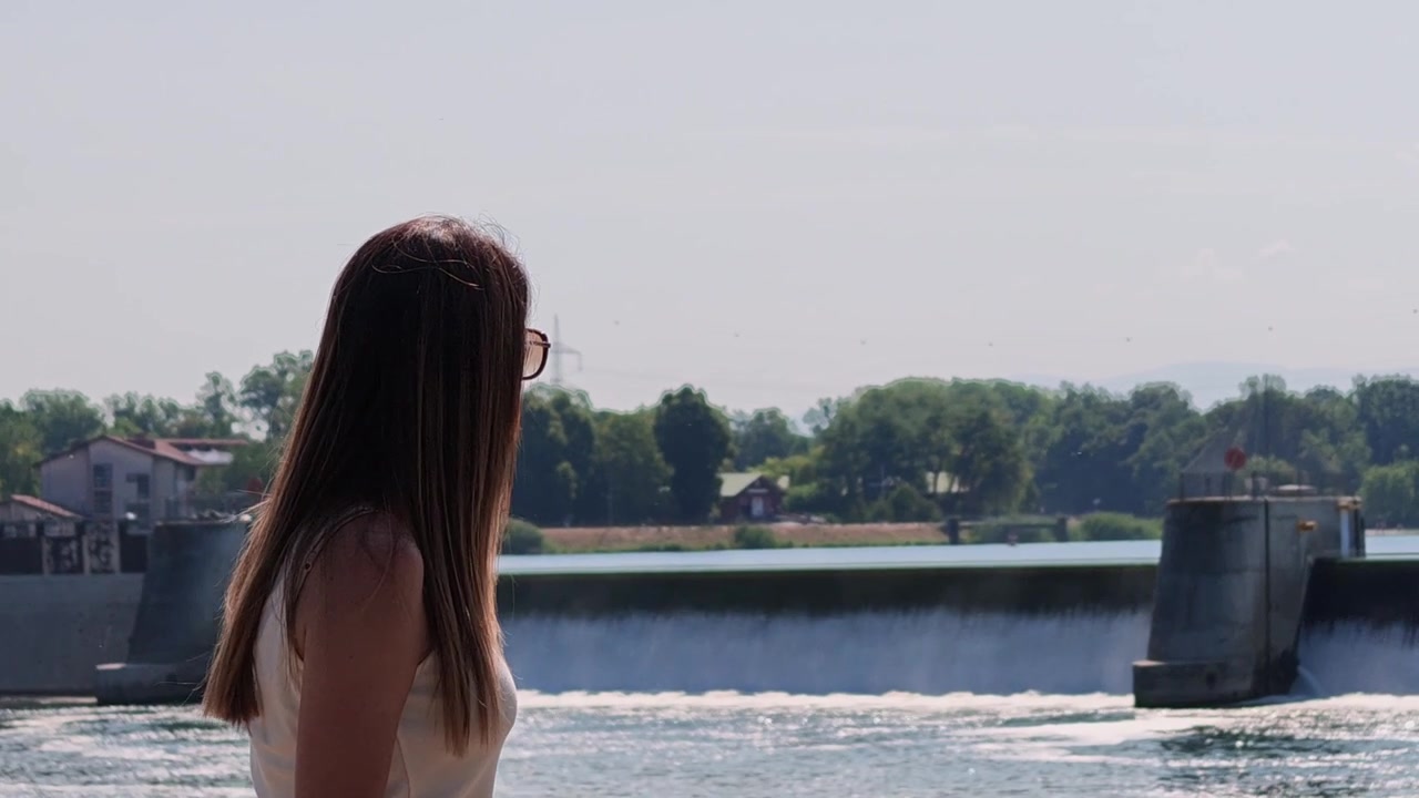 Woman with long hair looking at Breisach agricultural dam on the Rhine River, on the border between Germany and France
