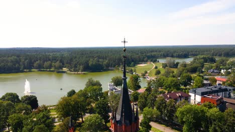 Aerial-shot-of-the-Catholic-Church-of-Saint-Mary's-Scapular-roof-and-the-cross-in-Druskininkai,-Lithuania-on-a-sunny-summer-day
