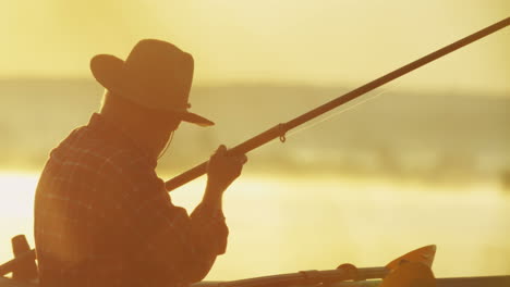 close-up view of a senior caucasian man in hat sitting in the boat on the lake and preaparing his road for fishing