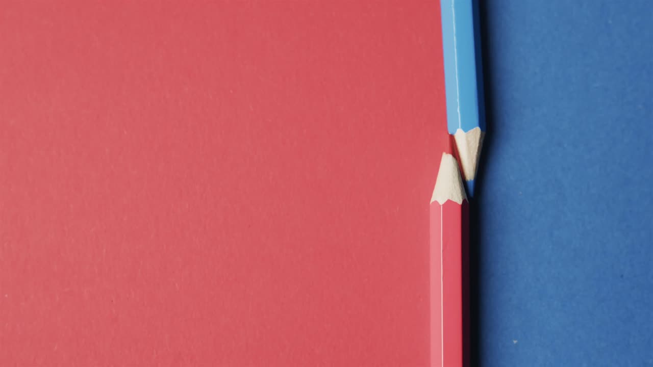 vista aérea de lápices de colores azules y rojos con espacio de copia en fondo rojo y azul, en cámara lenta