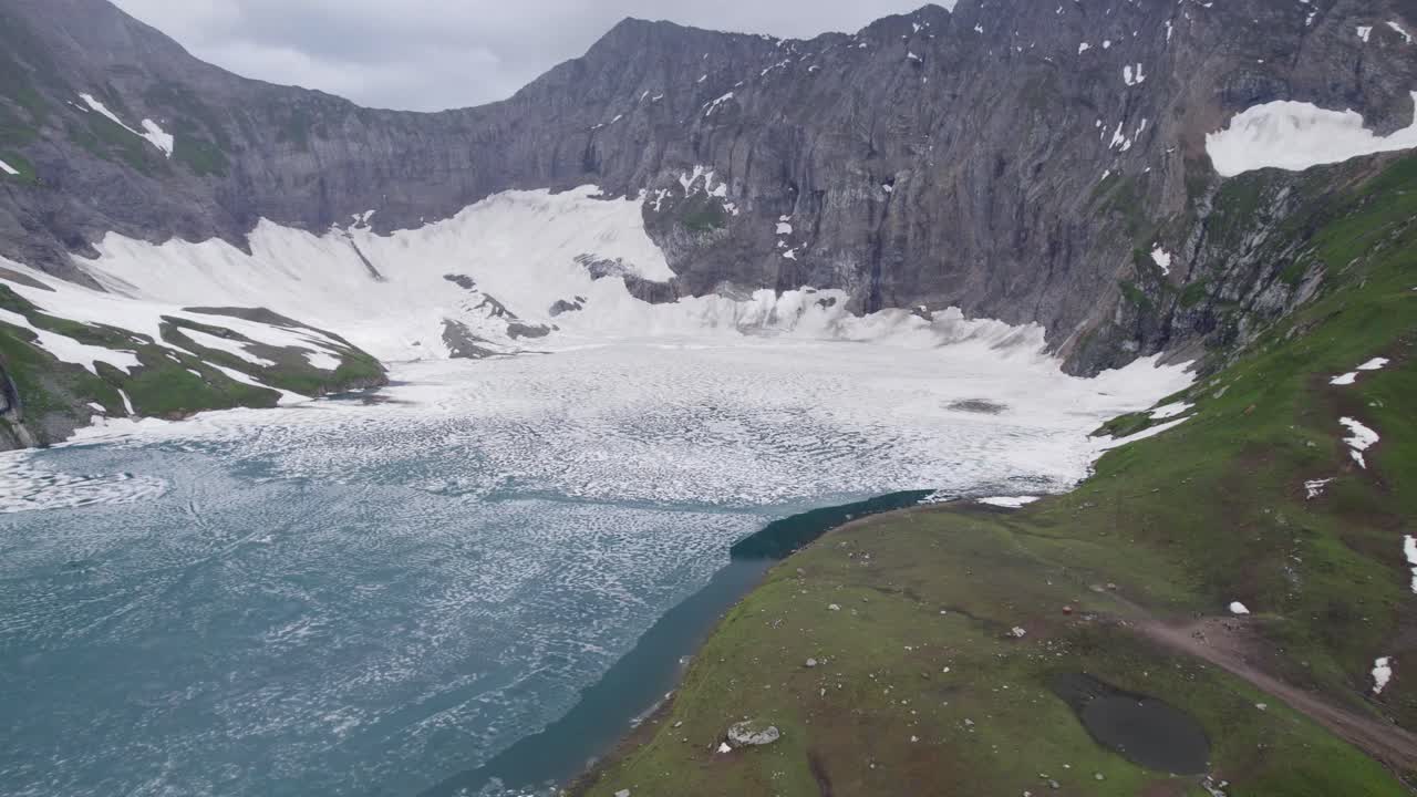 el lago ratti gali parcialmente congelado y las montañas cubiertas de nieve