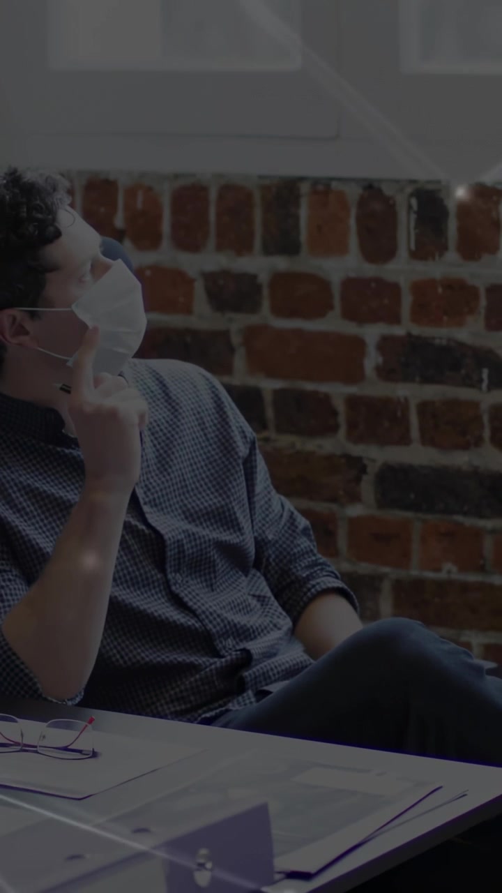 Vertical video: Man in office looking at window, adjusting mask for comfort, network overlay