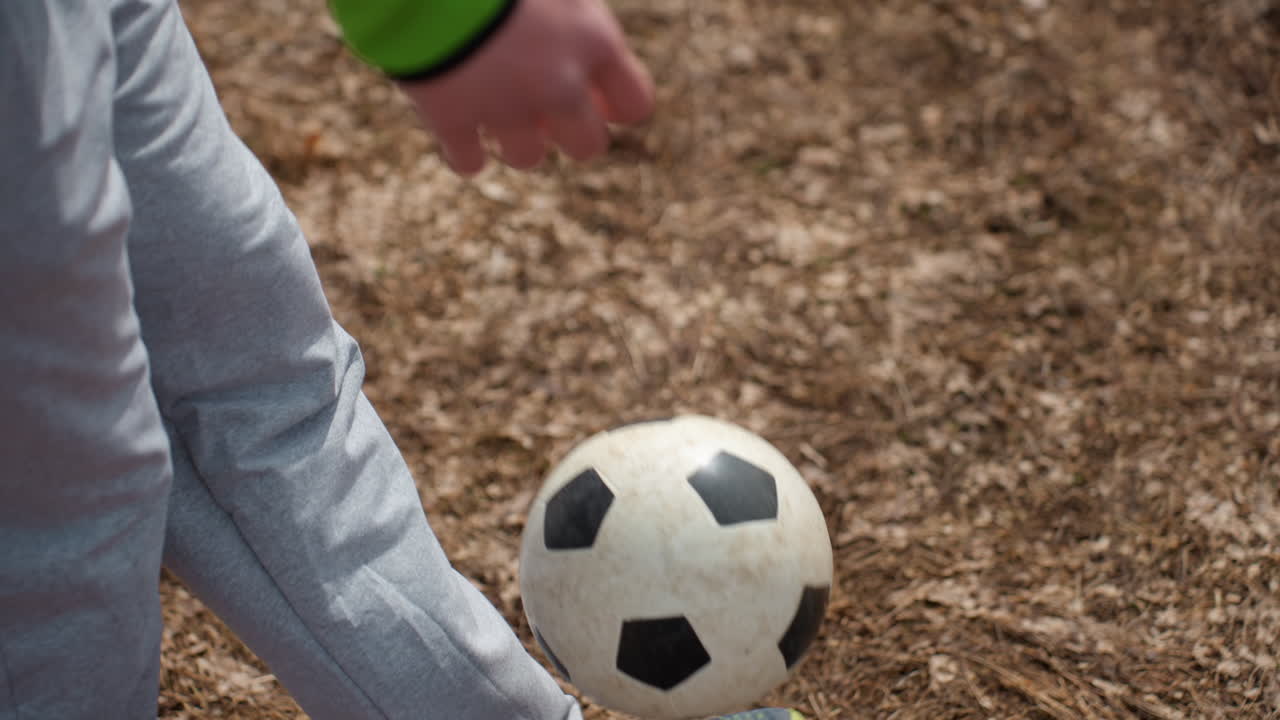 joven practicando habilidades con el balón al aire libre, chico joven haciendo malabares activamente con un balón de fútbol en el campo, niño caucásico joven mostrando juego de pies mientras equilibra un balón de fútbol durante una sesión de práctica al aire libre