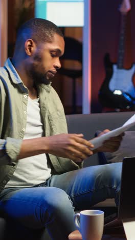 vertical video african american guy does research by reading articles and data driven papers