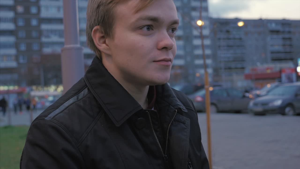 молодой человек ест сэндвич на улице