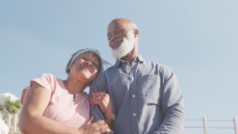 Happy-senior-african-american-couple-embracing-on-promenade-by-the-sea,-slow-motion