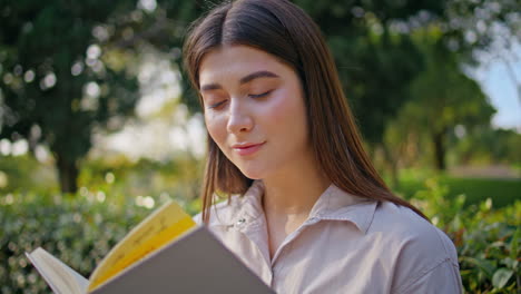 mujer pensativa de primer plano leyendo un libro en el parque verde retratando la tranquilidad.