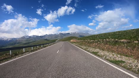 point of view driving a car on a road. mount elbrus is visible in the background.