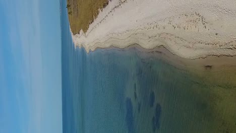 Vuelo-Aéreo-A-Lo-Largo-De-Una-Playa-De-Arenas-Blancas-Sobre-Aguas-Cristalinas-Del-Océano-Del-Golfo-En-Formato-Vertical