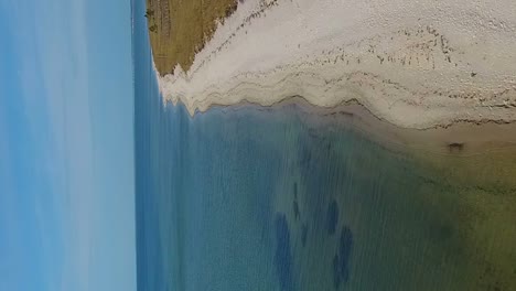 vuelo aéreo a lo largo de una playa de arenas blancas sobre aguas cristalinas del océano del golfo en formato vertical