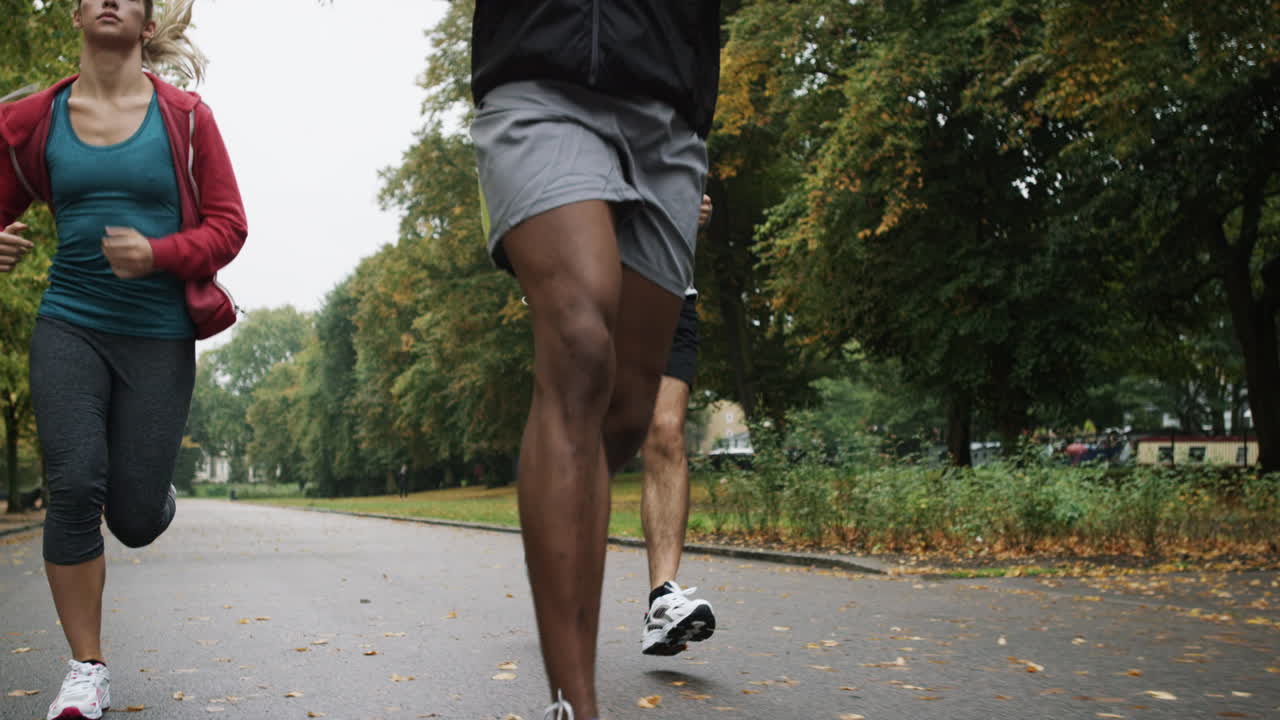 Group of runners running in park wearing wearable technology connected devices