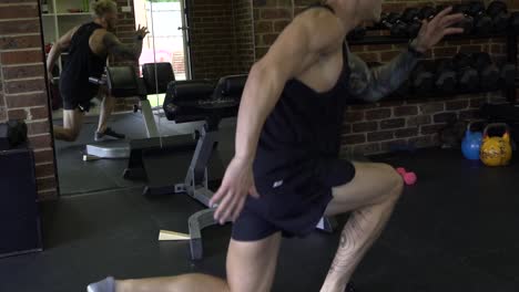 muscly man in home gym exercising split lunge jumps