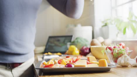 sección media de un hombre caucásico de pie en la cocina, cocinando la cena, aderezando la comida