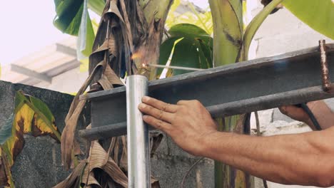 soldador profesional que emplea una máquina de soldadura industrial para unir dos piezas de metal creando una estructura metálica como parte de su trabajo diario en una pequeña empresa local