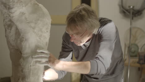 artist working on his plaster statue with intense concentration