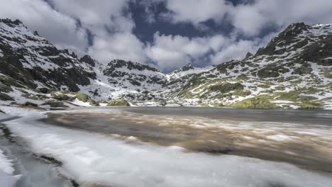 Wolken-Fließen-über-Einem-Zugefrorenen-See-Mit-Schneebedeckten-Bergen