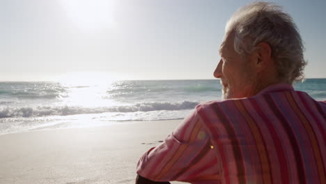 senior man sitting on the sand at the beach