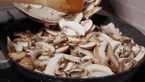 putting chopped mushrooms into frying pan - close up