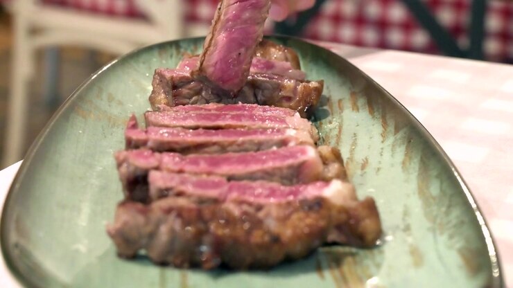 Steak Daging Sapi Panggang Iris di Piring Saji Diambil dengan Garpu di Restoran
