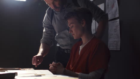 assertive investigator pointing to documents and interrogating female inmate