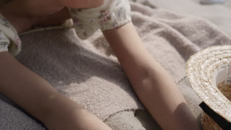 Playful-girl-touching-beach-sand-lying-on-mat-close-up.-View-gentle-woman-hands.