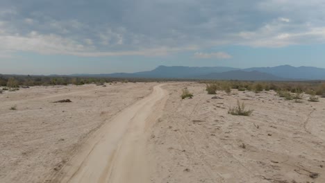 establishing drone shot of dirt road and mountains in rural mexico