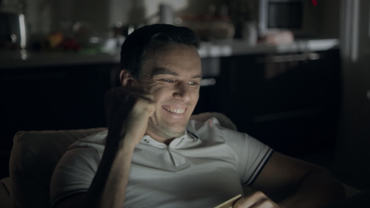 Closeup cheerful man making yes gesture in front of laptop screen at dark office