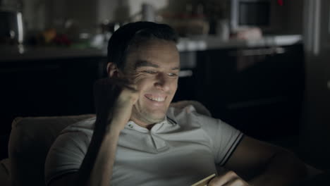 closeup cheerful man making yes gesture in front of laptop screen at dark office