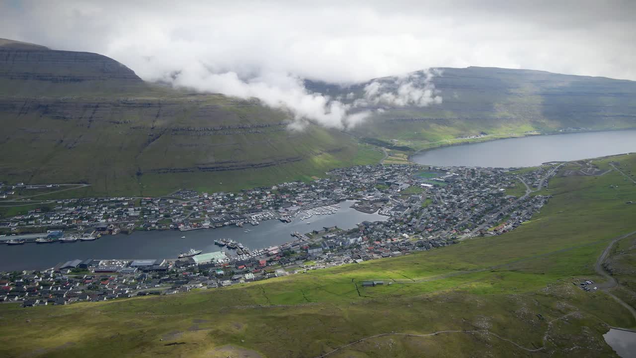 페로 제도에서 두 번째로 큰 도시인 클라크스비크 (klaksvik) 는 산과 바다 사이에 자리 잡고 있으며, 배가 있는 항구, 다채로운 집들, 그리고 풍경을 고 있는 낮은 구름을 보여줍니다.