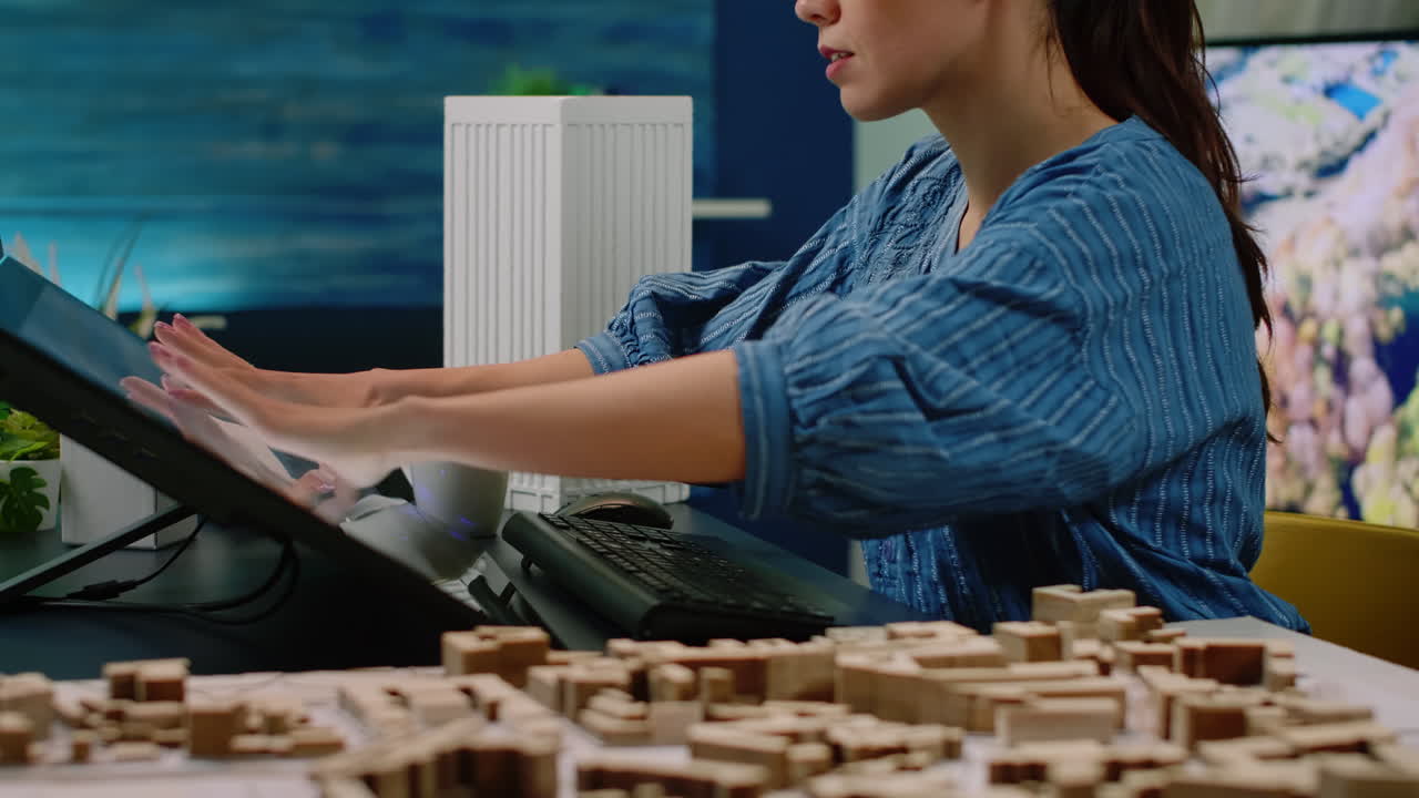 Close up of hands using touch screen monitor with building model